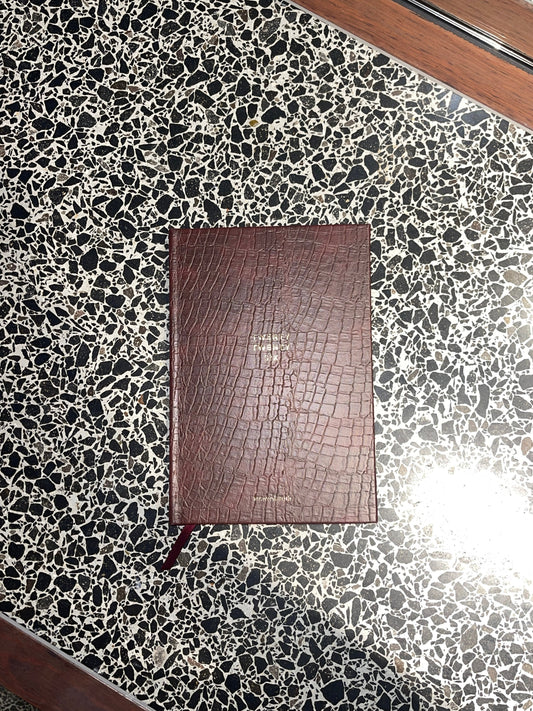 Brown leather notebook on a black and white speckled surface