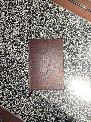 Brown leather notebook on a black and white speckled surface
