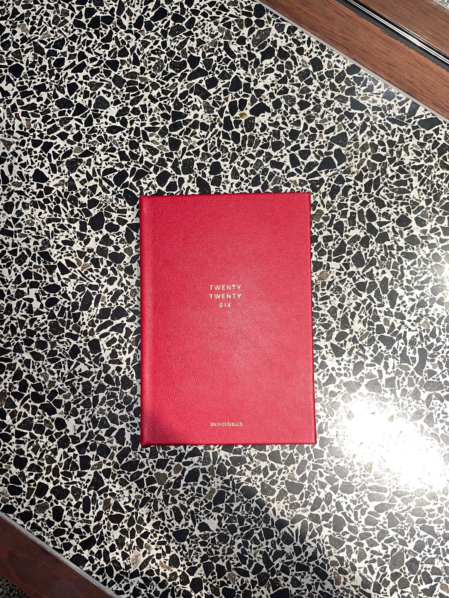 Red book with white text on a black and white speckled surface